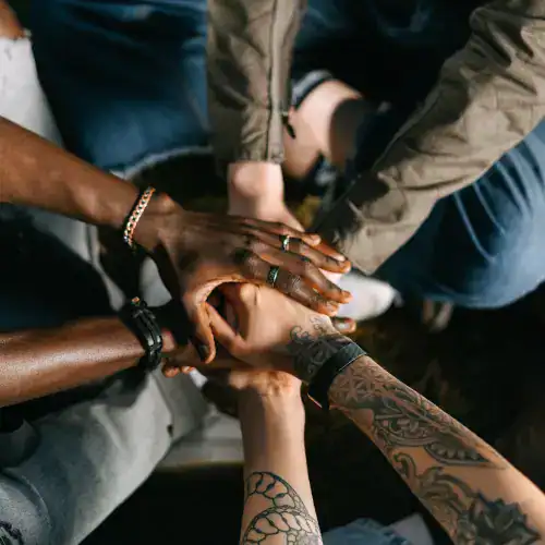 Diverse hands stacked together symbolizing unity, teamwork, and collaboration in a community-focused environment. Perfect for keywords related to global connection, inclusivity, and social impact.